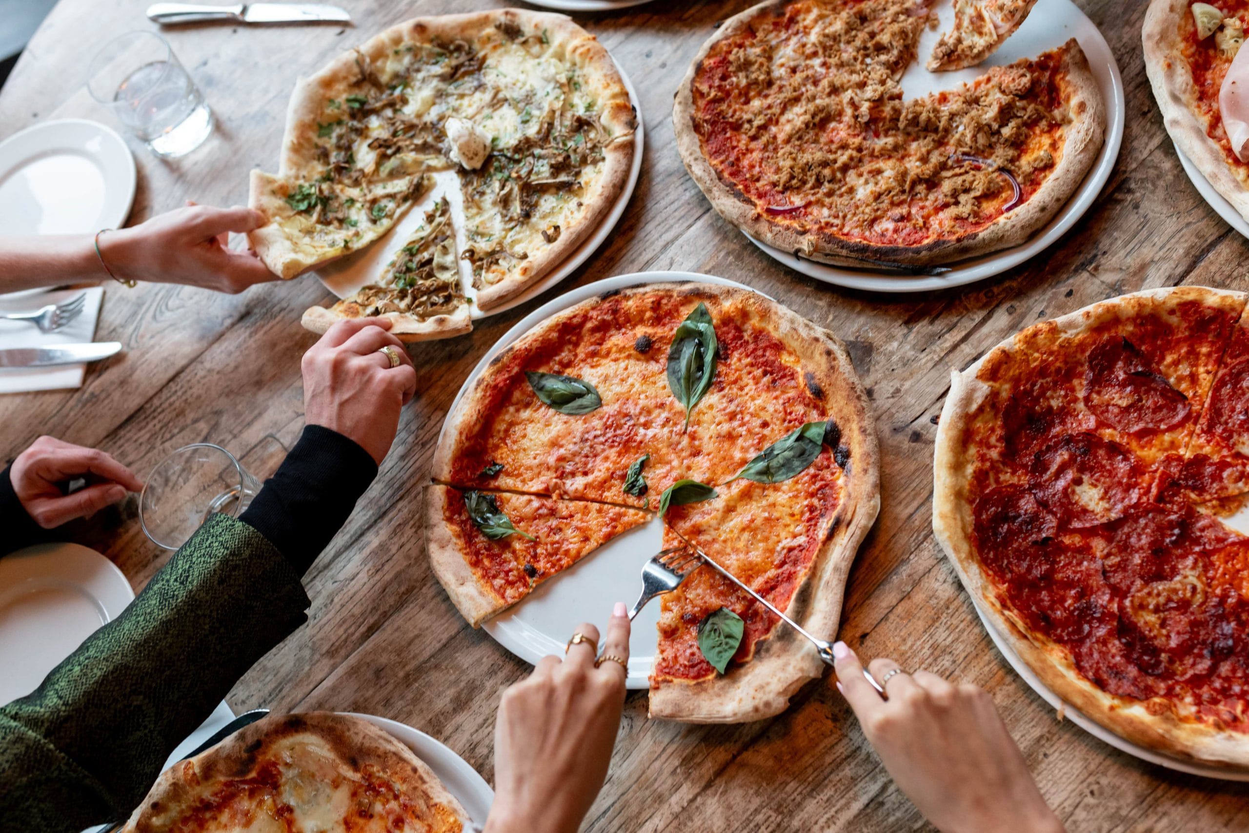 pizza's Tafel vol pizza's waar stukken uit gesneden en gepakt worden bij Mercatu